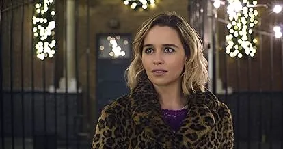 Emilia Clarke wearing a leopard print coat, standing outdoors at night with festive lights behind her