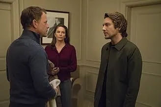 Three characters in a tense conversation indoors, referencing Gregory the brilliant but abrasive diagnostician.