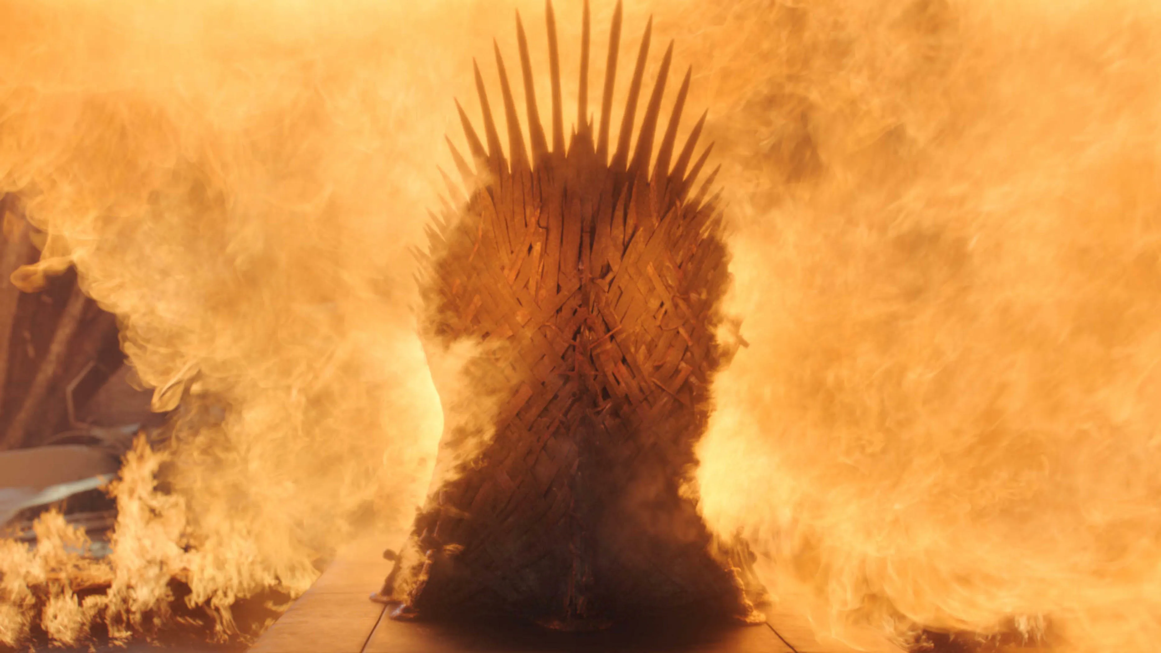 Iron Throne from a fantasy TV show engulfed in flames with intense fire surrounding the iconic crown seat.