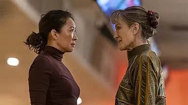 Two women facing each other intensely in a scene from a spy thriller cat-and-mouse chase between investigator and assassin.