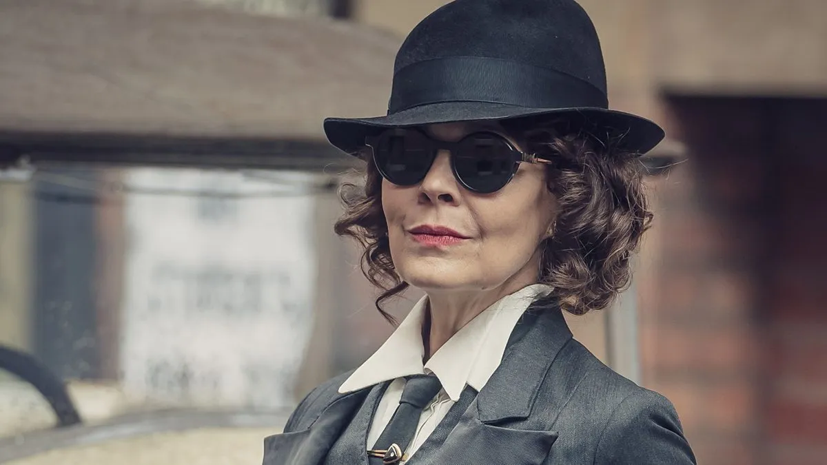 A confident character from Peaky Blinders wearing a black hat and sunglasses, embodying the show's gritty TV drama style.