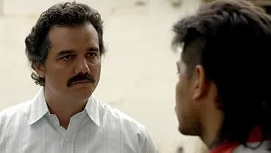 Scene from a crime drama TV show depicting the rise and fall of Colombian drug lord Pablo Escobar in intense conversation.