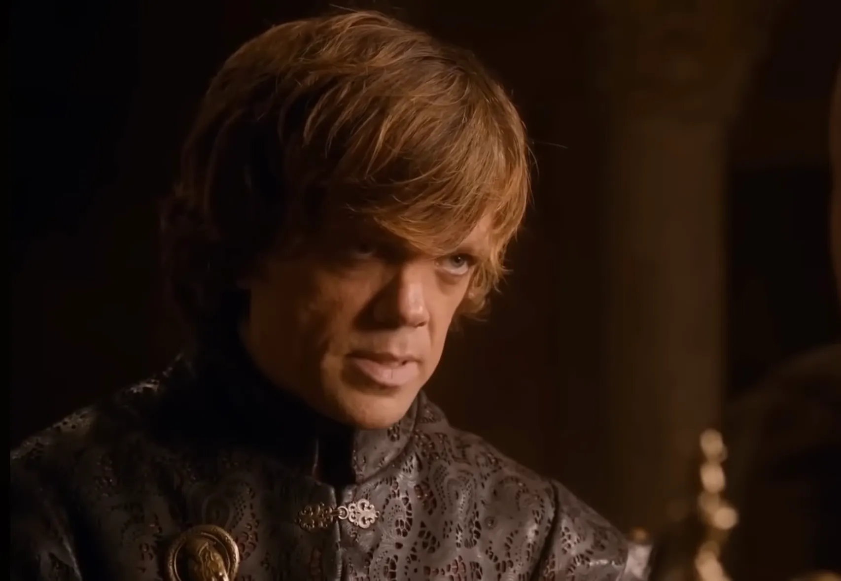Tyrion Lannister in detailed dark clothing with serious expression in a dimly lit medieval setting.