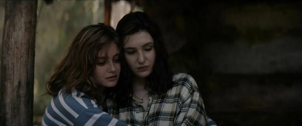Two young women in casual clothes embracing, depicting a survival thriller TV show about a stranded girls’ soccer team.