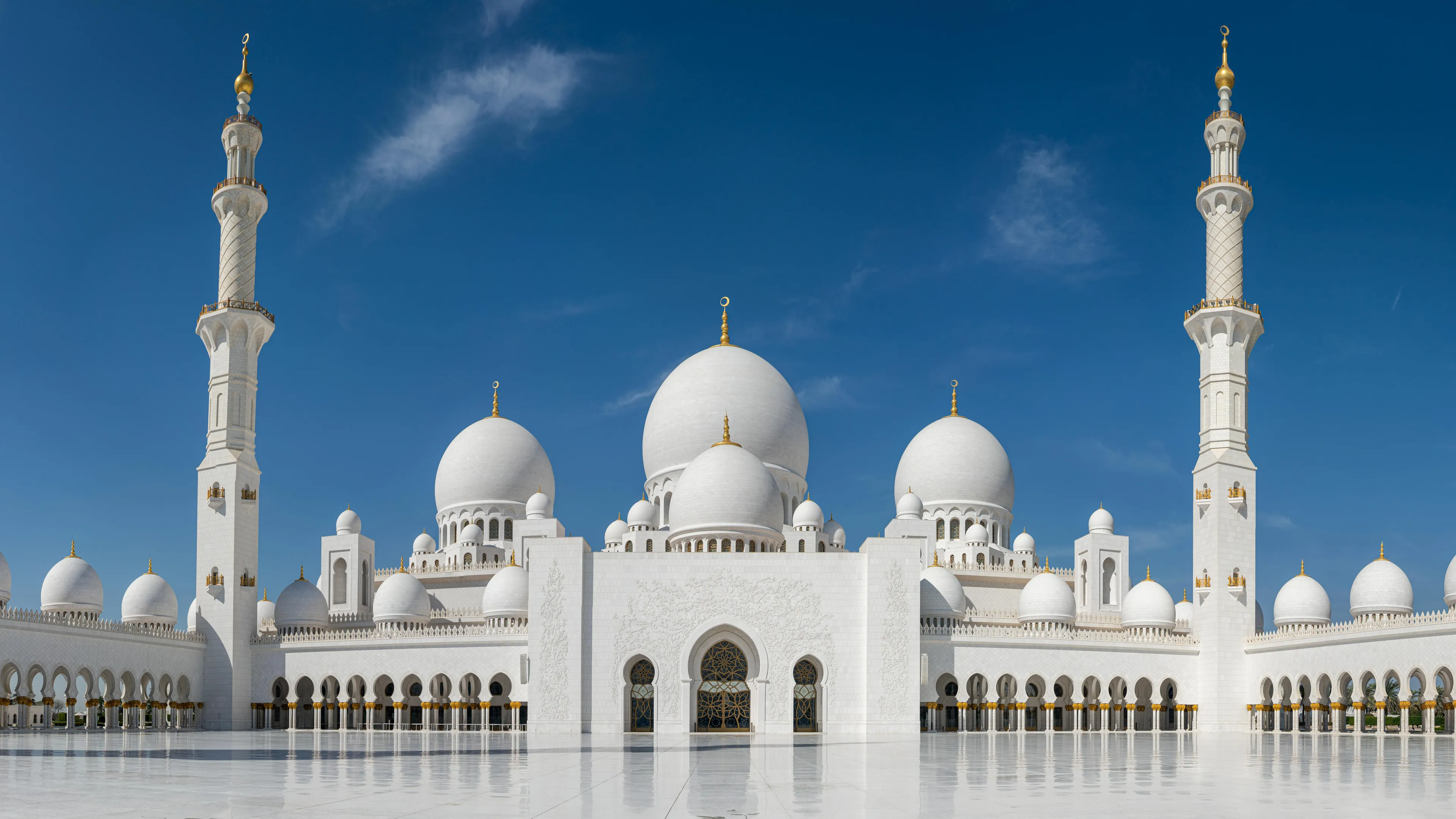 Sheikh Zayed Grand Mosque in Abu Dhabi with white domes and minarets under a bright blue sky, guess the country quiz.