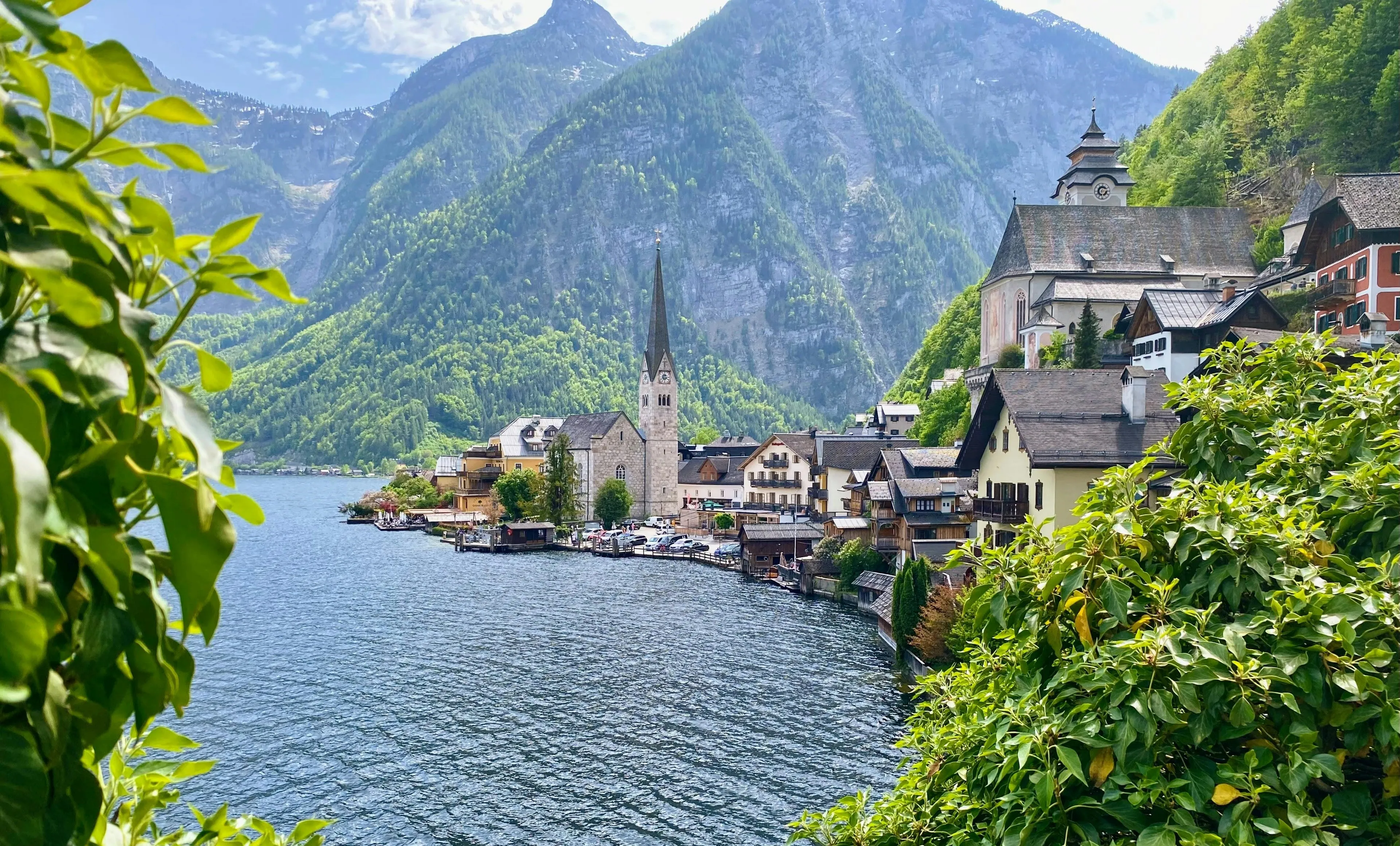 Scenic lakeside village with alpine mountains in the background, representing a landlocked European country landscape.