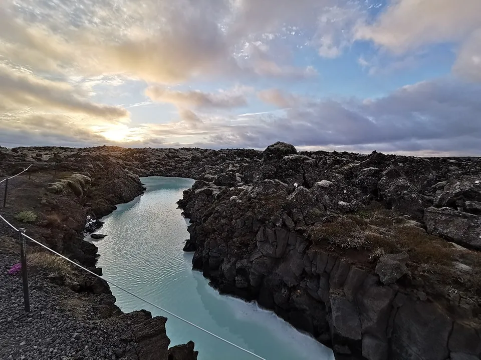 Rocky landscape with a narrow milky blue river under a cloudy sky, part of guess countries from a single picture challenge.
