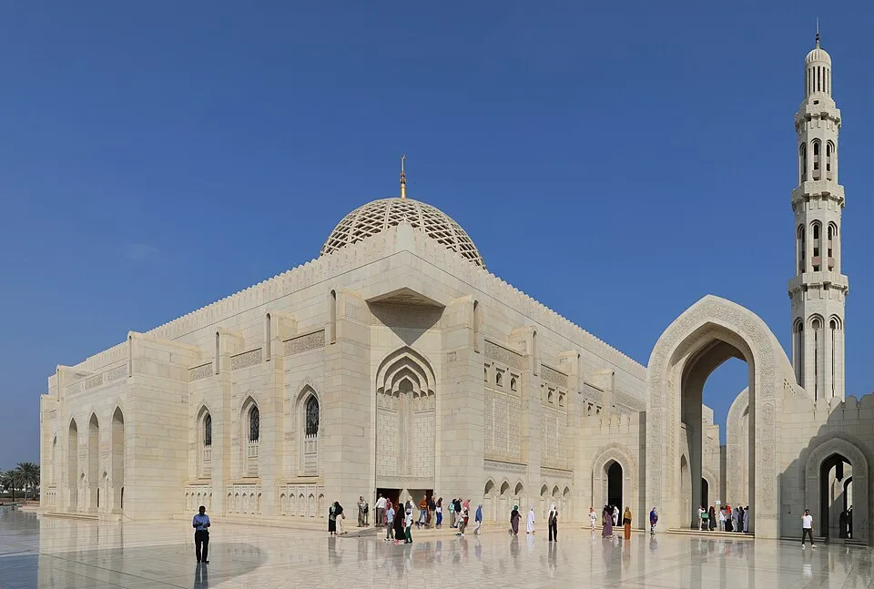 Sultan Qaboos Grand Mosque exterior with visitors under a clear blue sky, highlighting Oman country landmark architecture.