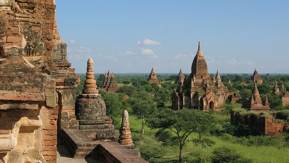 Ancient temples and pagodas in a lush green landscape representing a Southeast Asian country for guessing countries.