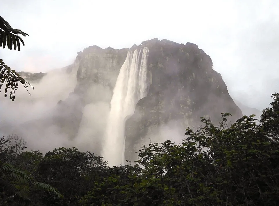 Angel Falls waterfall cascading from a rocky cliff surrounded by mist and lush green foliage in South America.