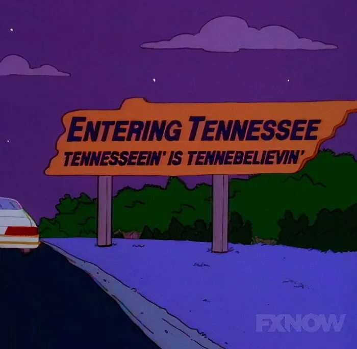 Animated scene from The Simpsons showing a humorous Tennessee road sign at night, featuring best signs from the show.