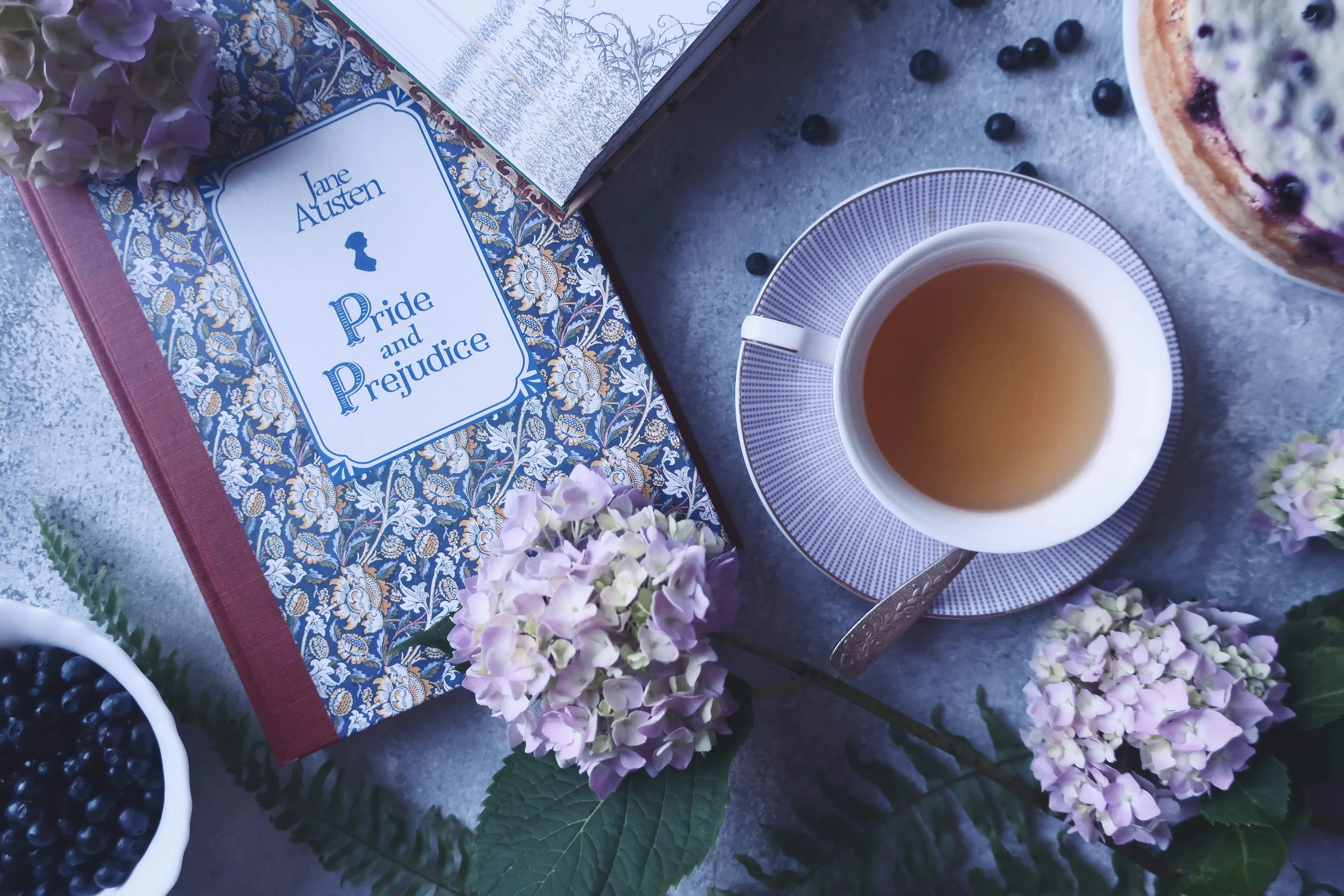 Jane Austen Pride and Prejudice book with tea and flowers, representing literature and central conflict theme.