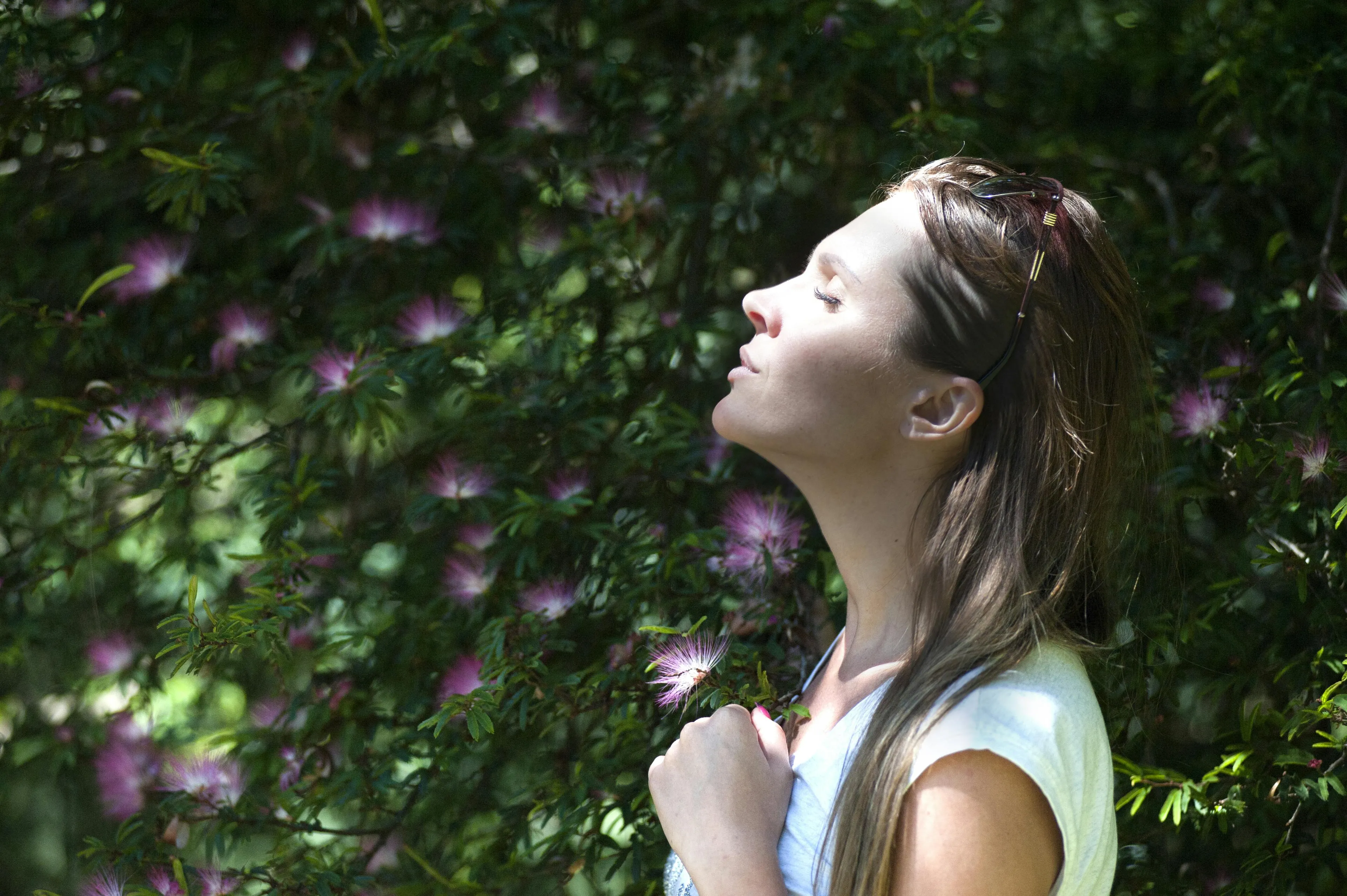 Young woman outdoors breathing deeply among flowers, symbolizing aerobic and anaerobic respiration concepts in science.