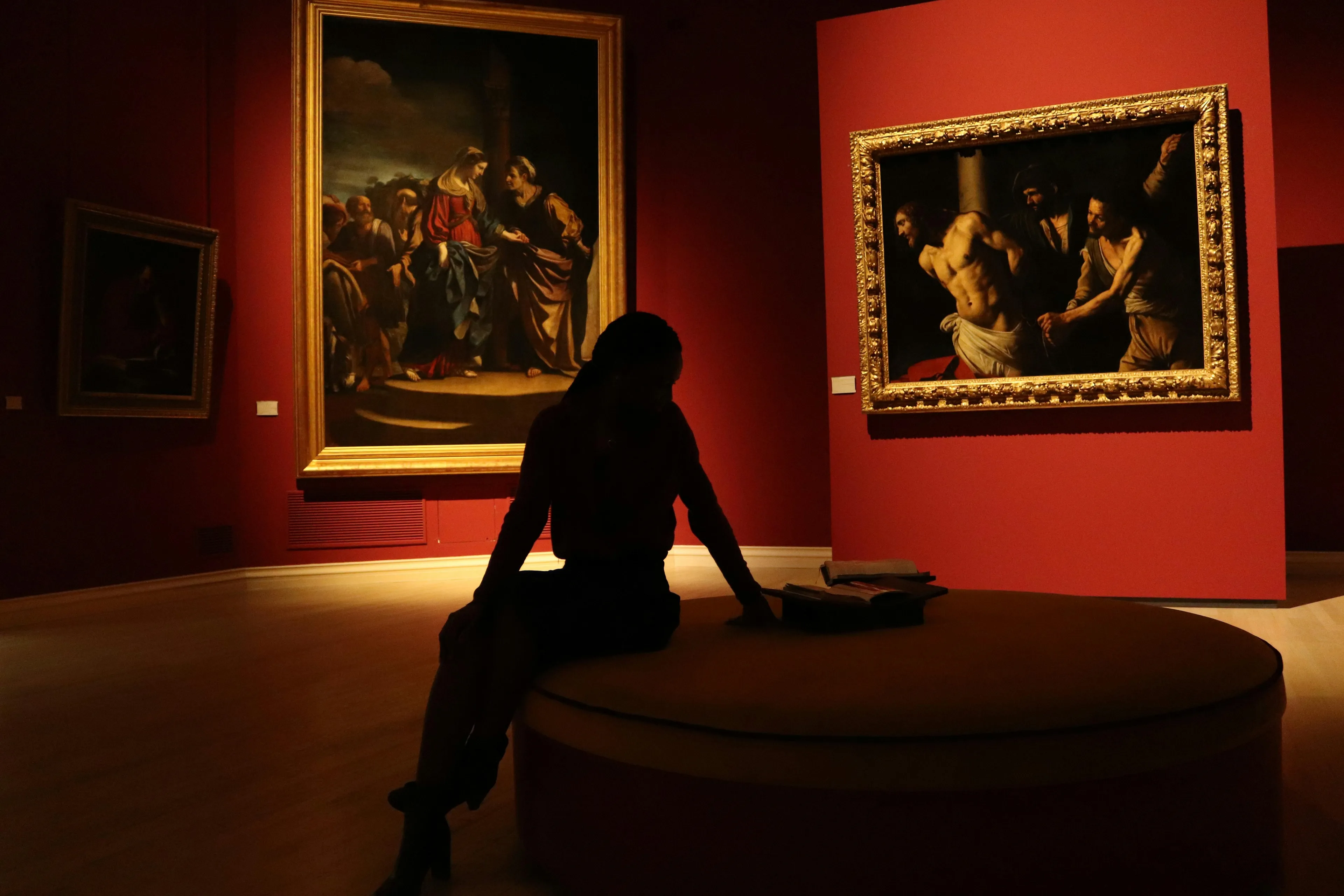 Silhouette of a person sitting in an art gallery with classic paintings illustrating principles of design balance.