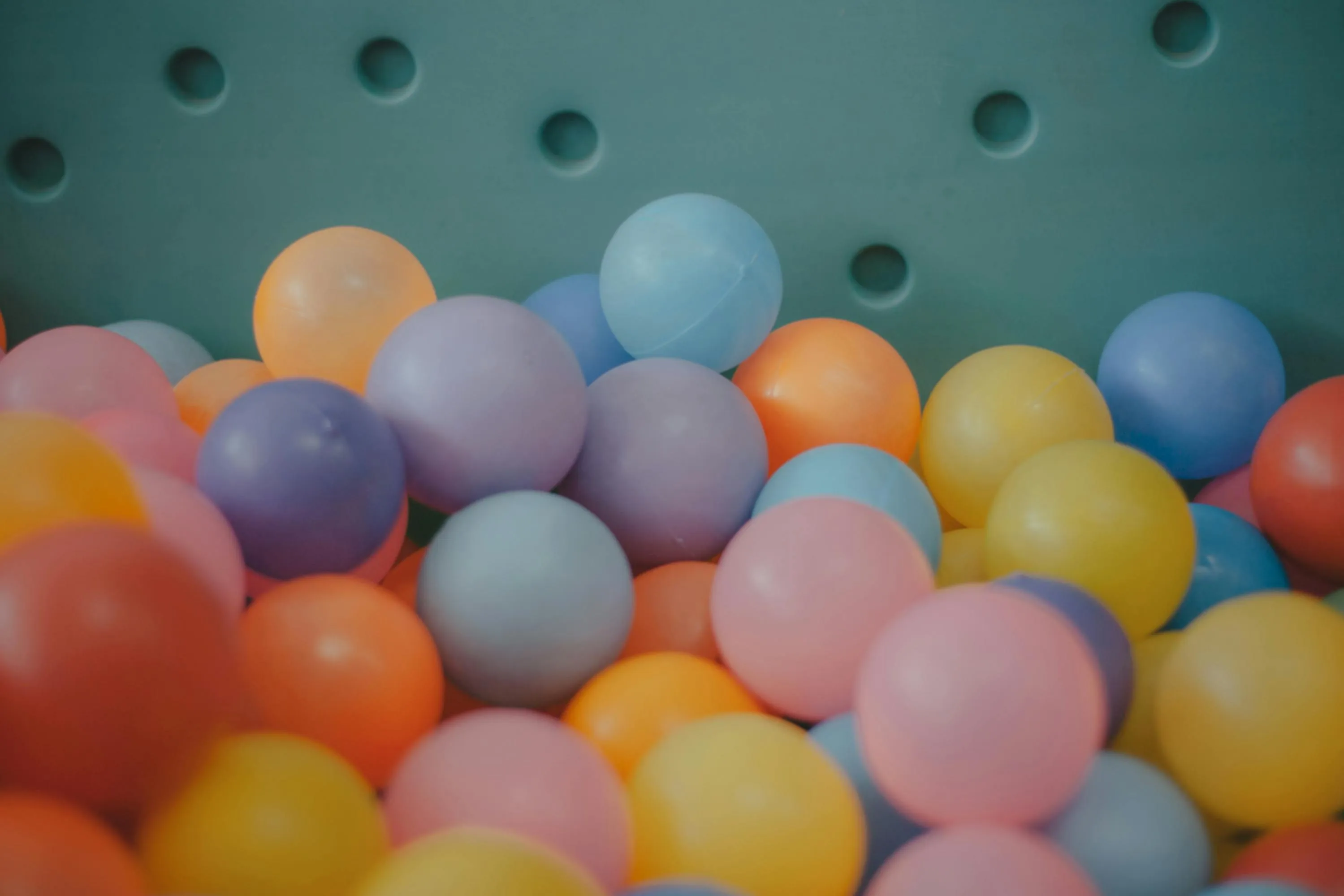 Colorful plastic balls in a box representing a math probability problem about picking a blue ball from red, blue, and green balls.