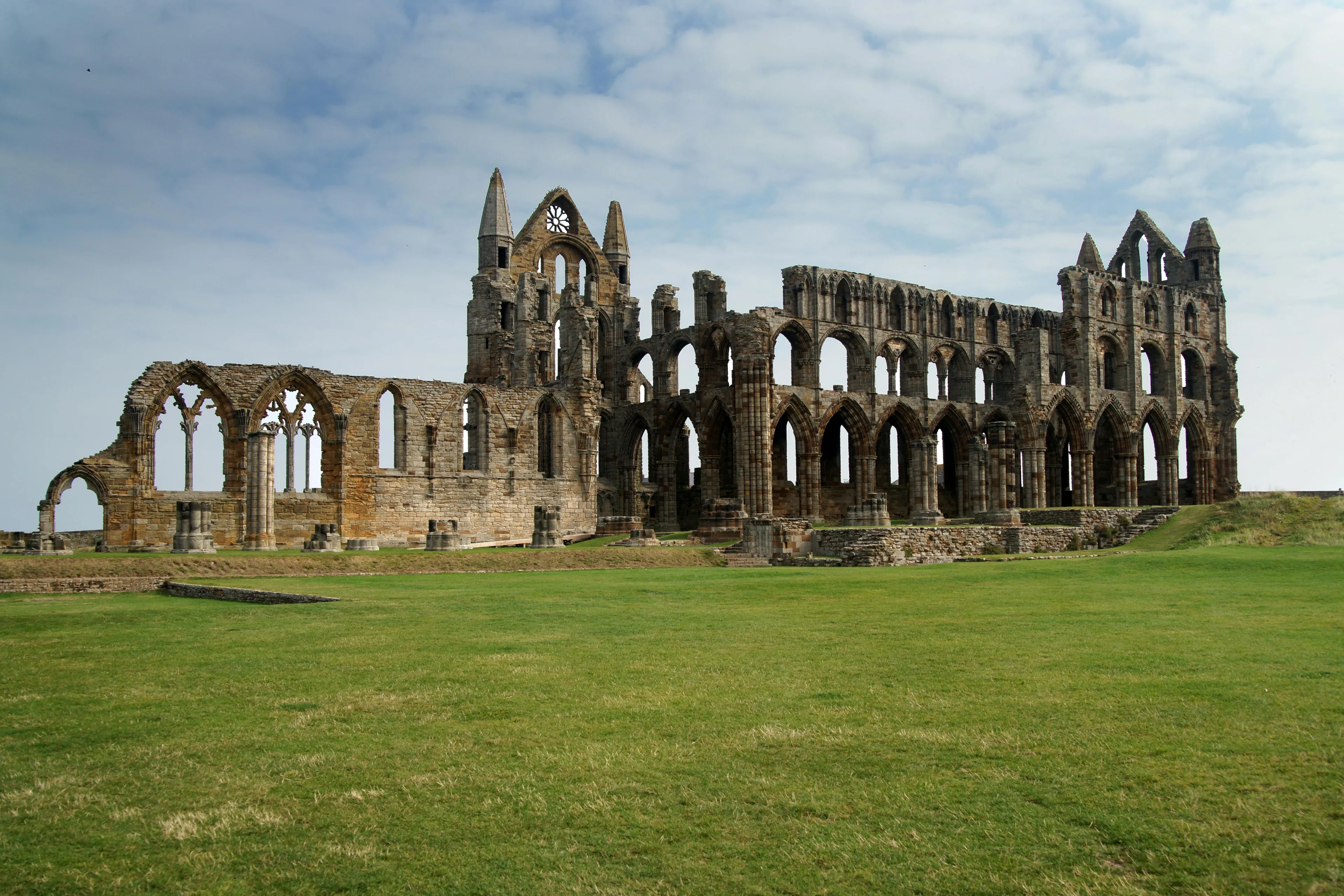 Ruins of a historic stone abbey under a cloudy sky with green grass in the foreground, representing the United Kingdom.