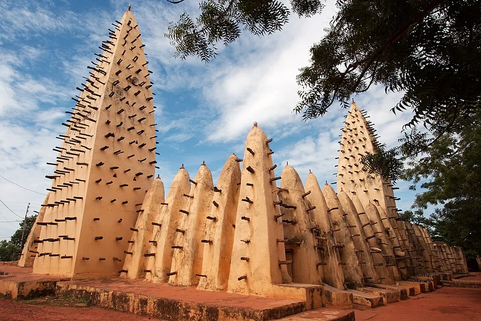 Traditional Sudano-Sahelian architecture of the Great Mosque in Burkina Faso under a partly cloudy sky.