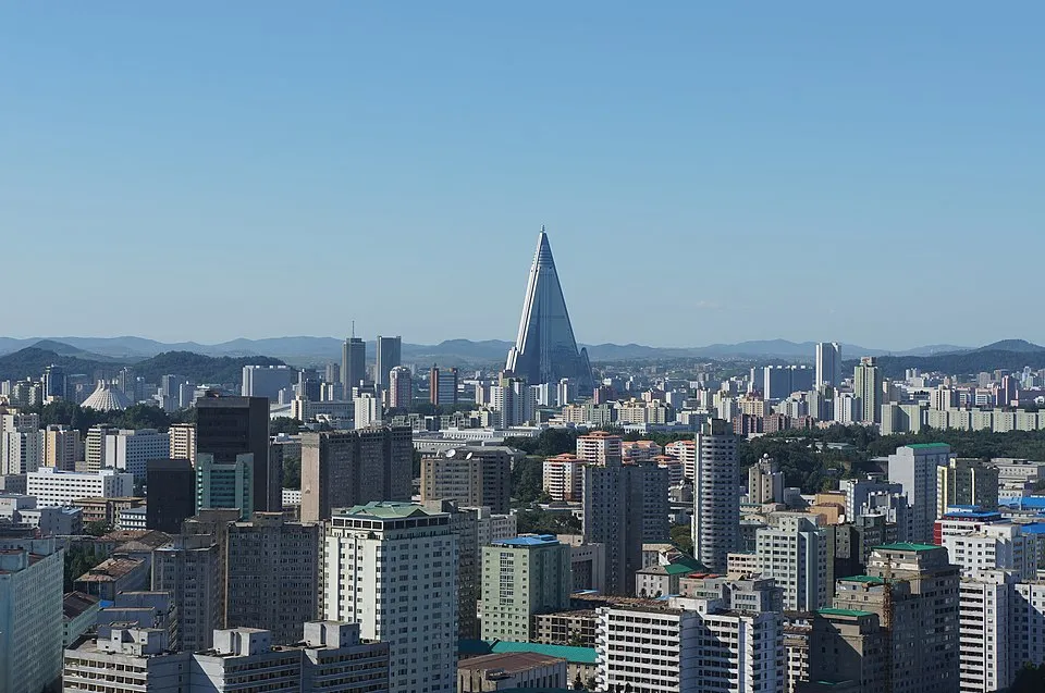 Cityscape of Pyongyang featuring the Ryugyong Hotel in North Korea with clear blue sky and distant mountains.