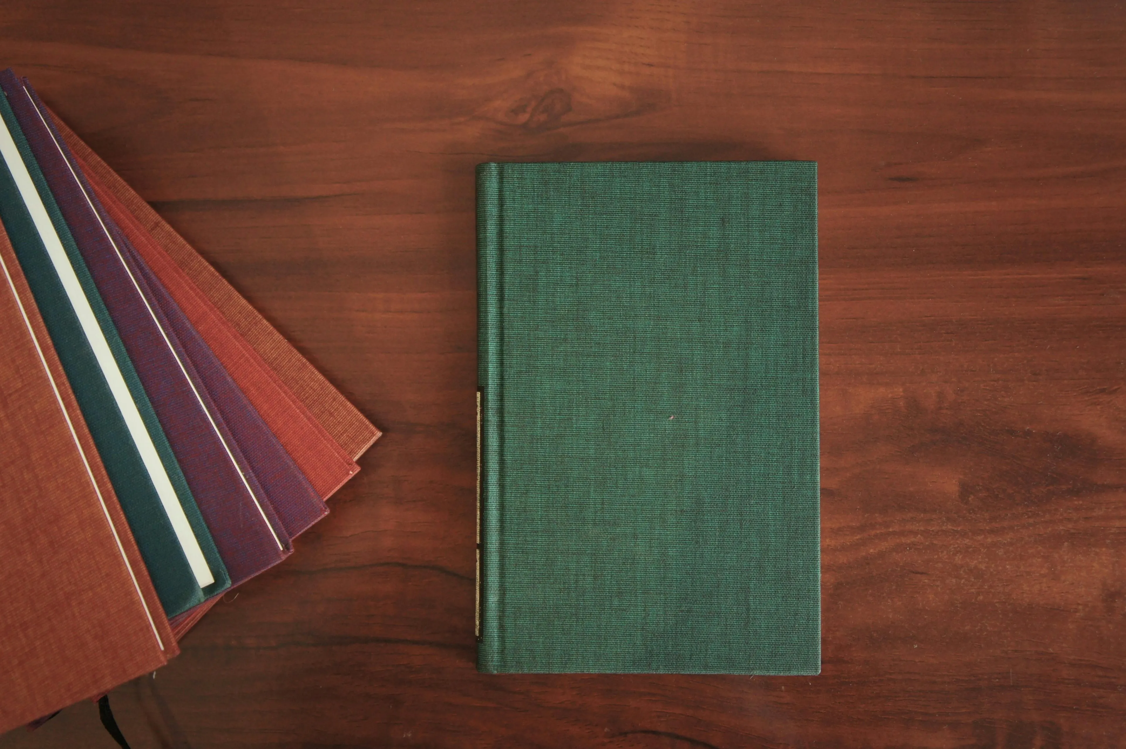 Stack of closed books resting on a wooden table illustrating physics concept of why book does not fall through surface