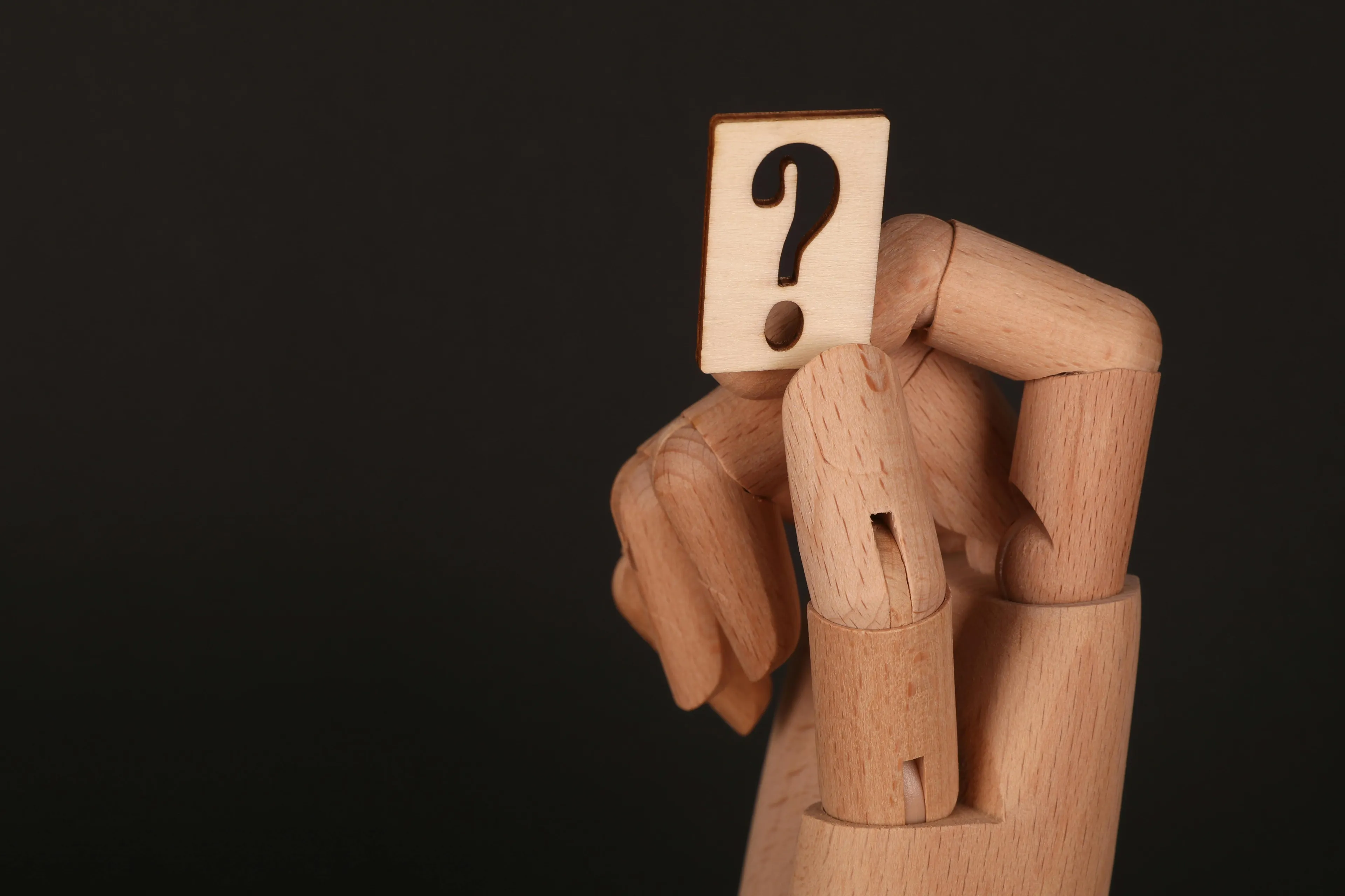 Wooden mannequin with a question mark face symbolizing school questions in literature about human qualities given to objects.