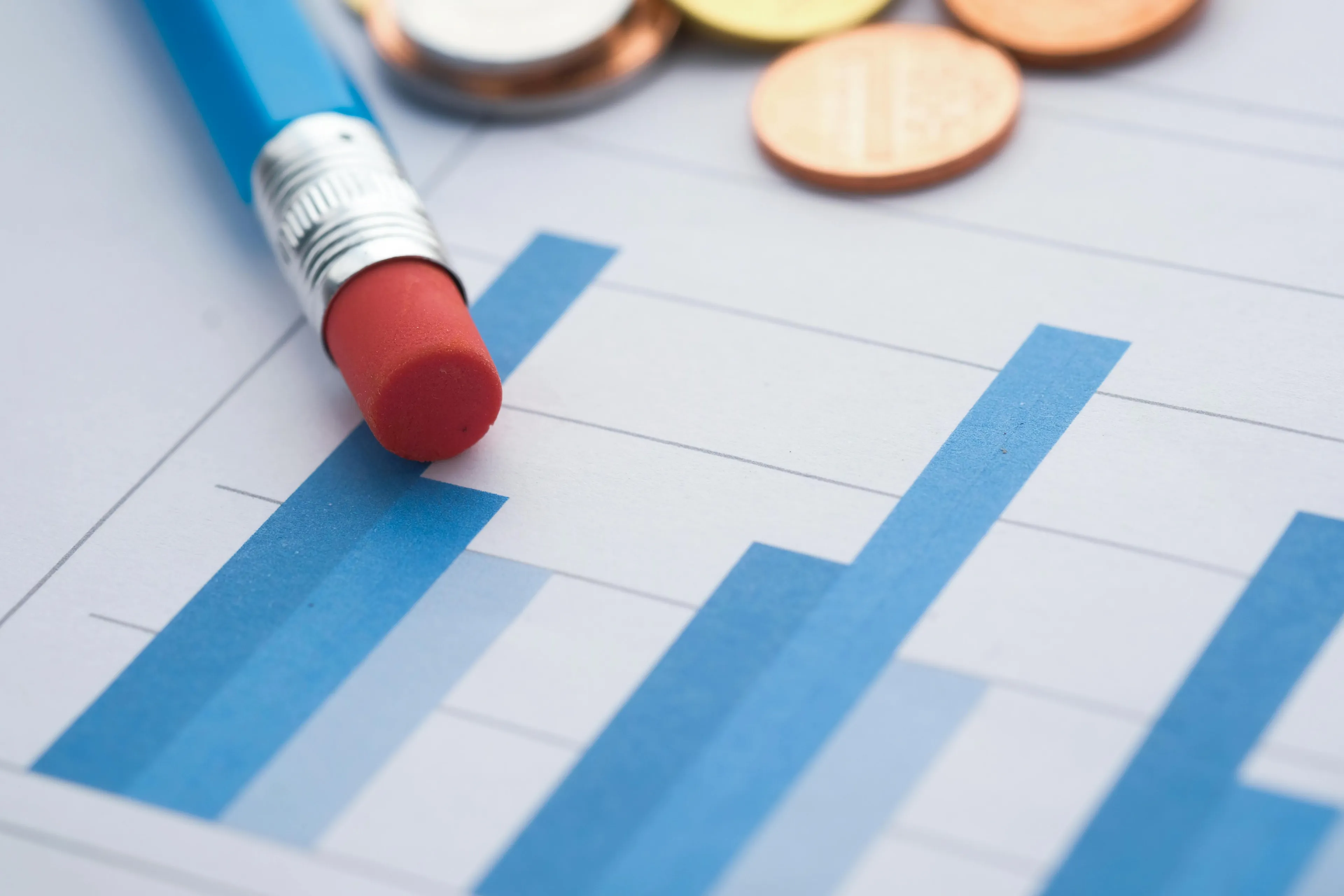 Close-up of a bar graph with rising sales data, a pencil eraser, and coins illustrating ice cream sales in summer months.
