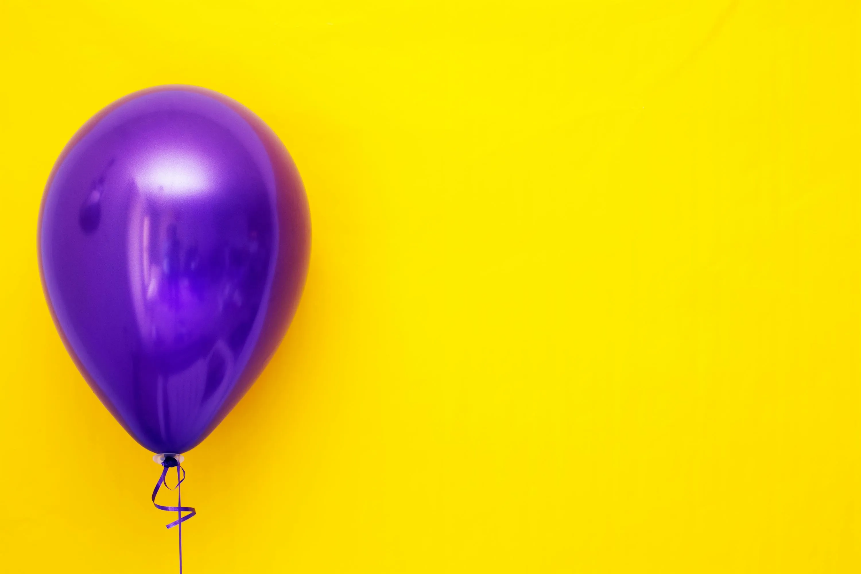 Purple balloon against a yellow background illustrating physics concept of why a balloon shrinks when placed in a freezer.