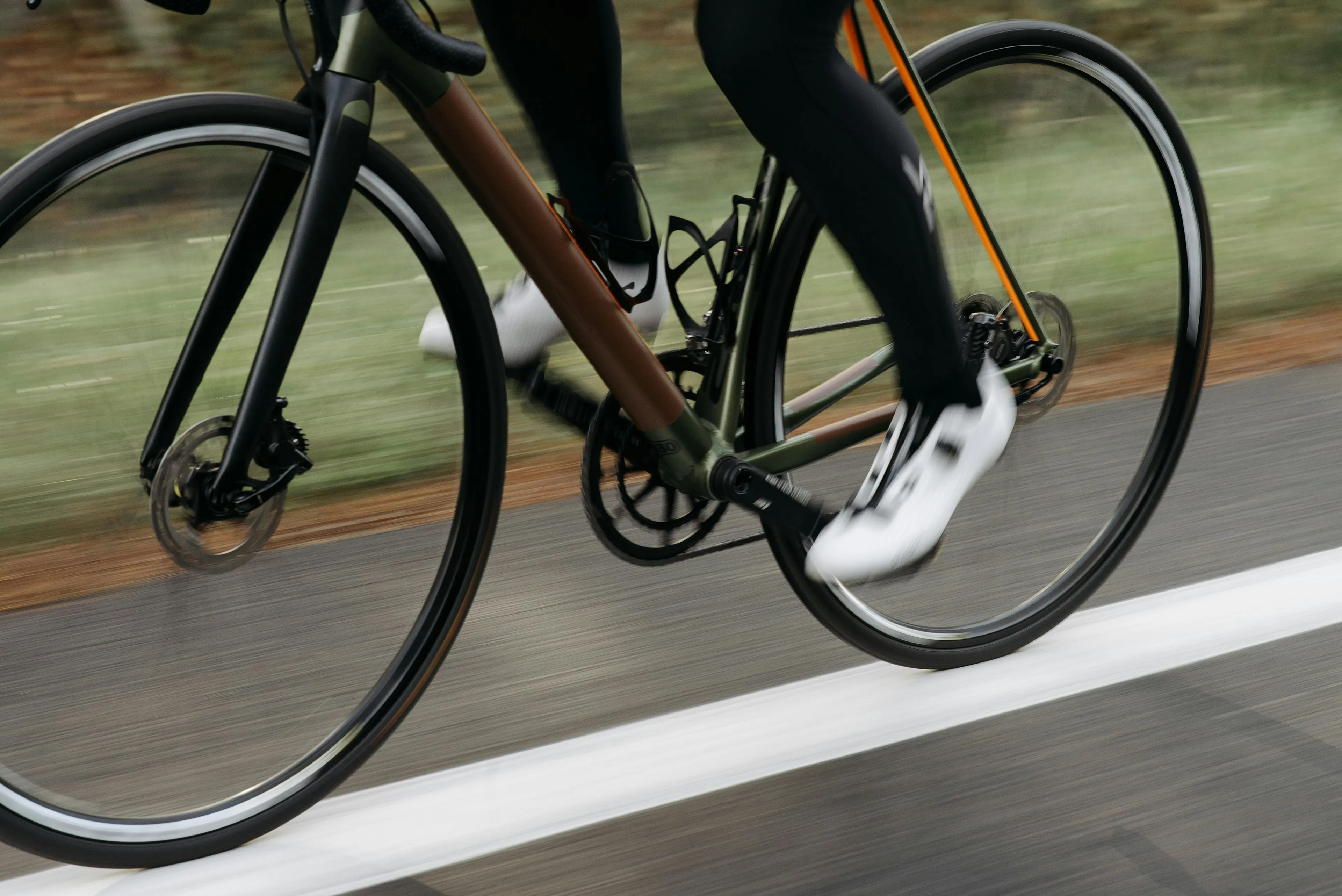 Close-up of a cyclist pedaling on a flat road illustrating physics concepts of motion and inertia in cycling.