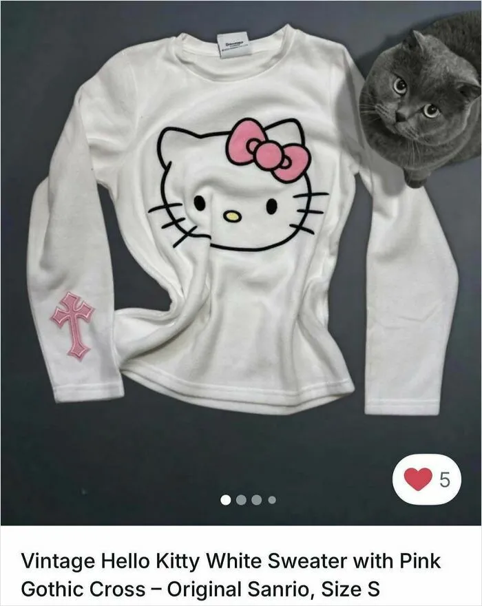 Gray cat sitting next to a white Hello Kitty sweater with pink bow and gothic cross on sleeve in Vinted ads.