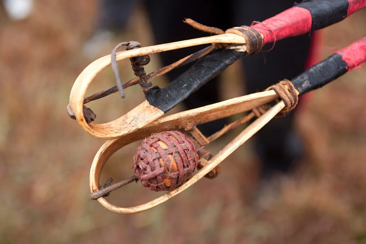 Two handmade stickball bats with wrapped handles and a woven ball ready to play the childhood game stickball outdoors.