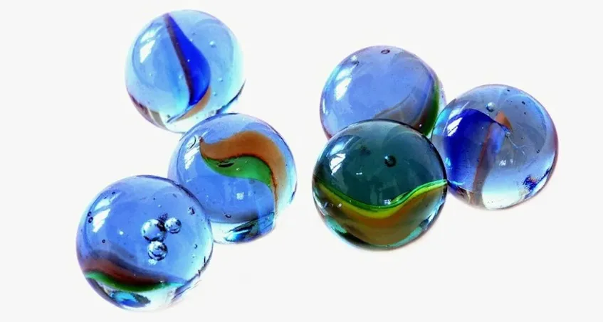 Colorful glass marbles with swirled patterns, reflecting light on a clean white background for childhood game replay.