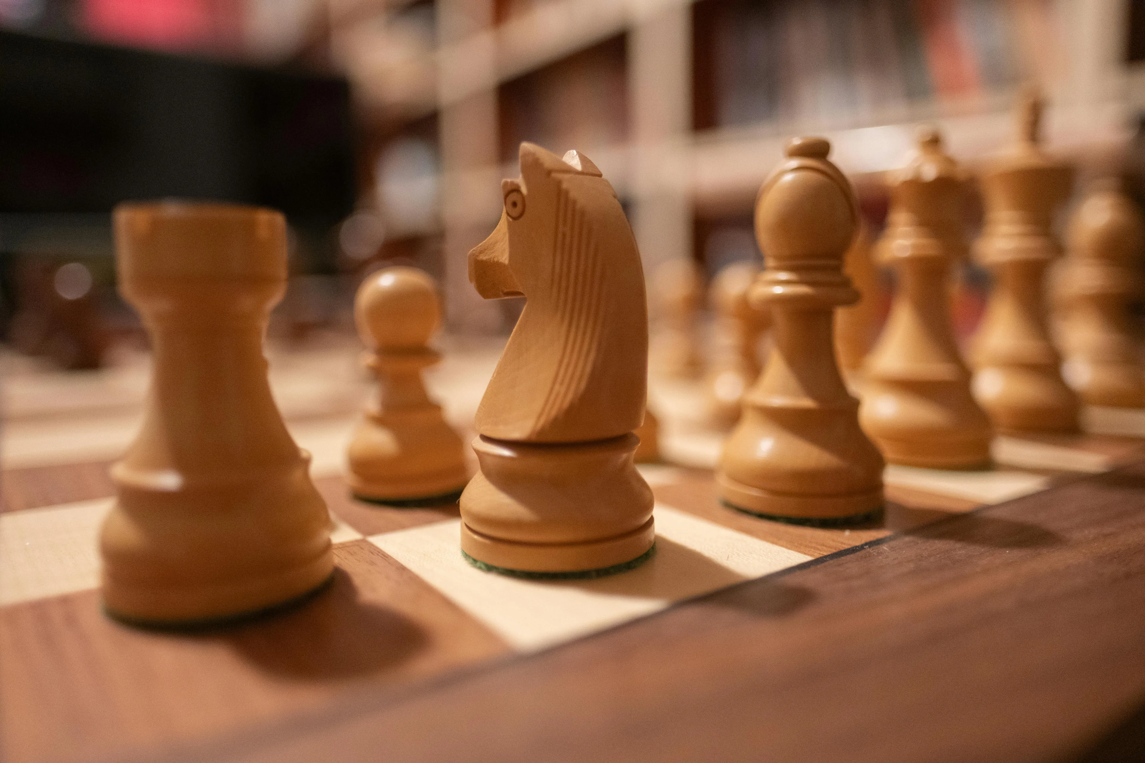 Close-up of wooden chess pieces arranged on a chessboard ready for a strategic childhood game replay.