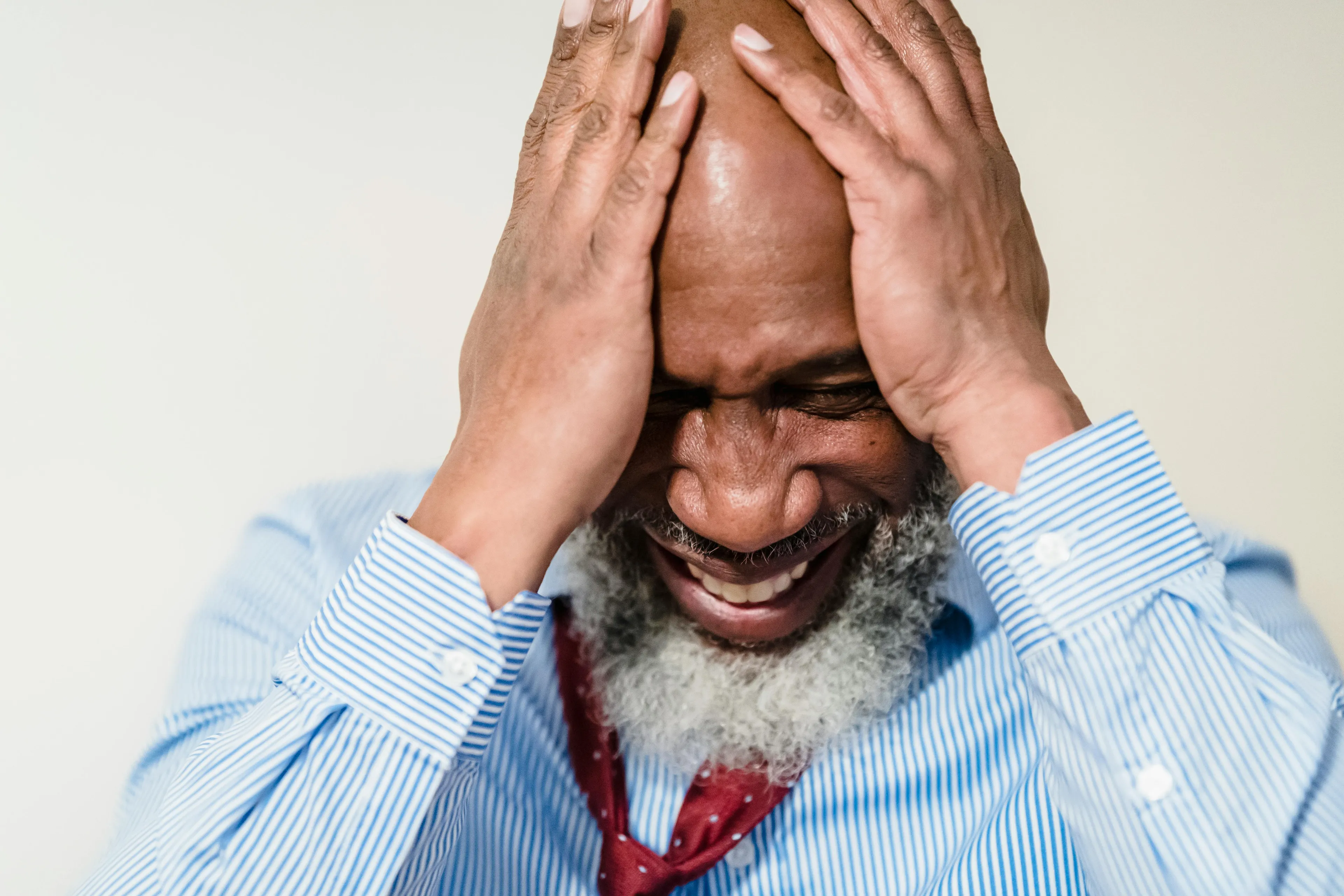 Man in striped shirt smiling with hands on head, showing reaction to last minute plan cancellations in sitcom quiz context.