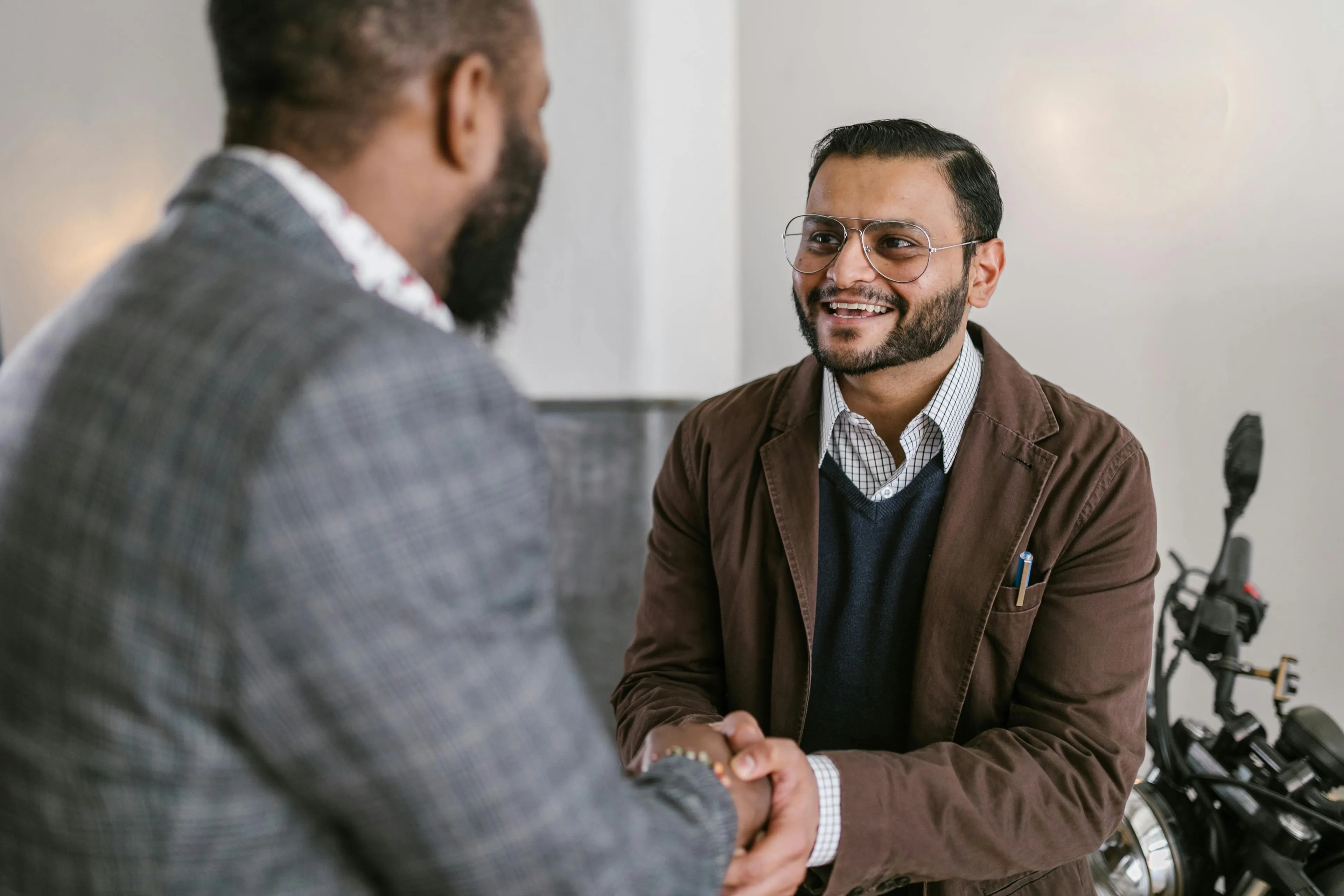 Two men shaking hands and smiling during a friendly meeting focusing on first impressions in new acquaintances.