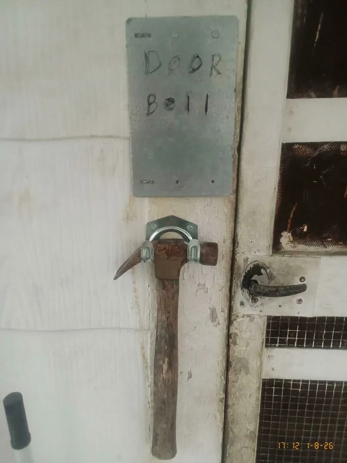 Hammer used as a doorbell with a hand-drawn sign, an example of if it's stupid but it works then it's not stupid.