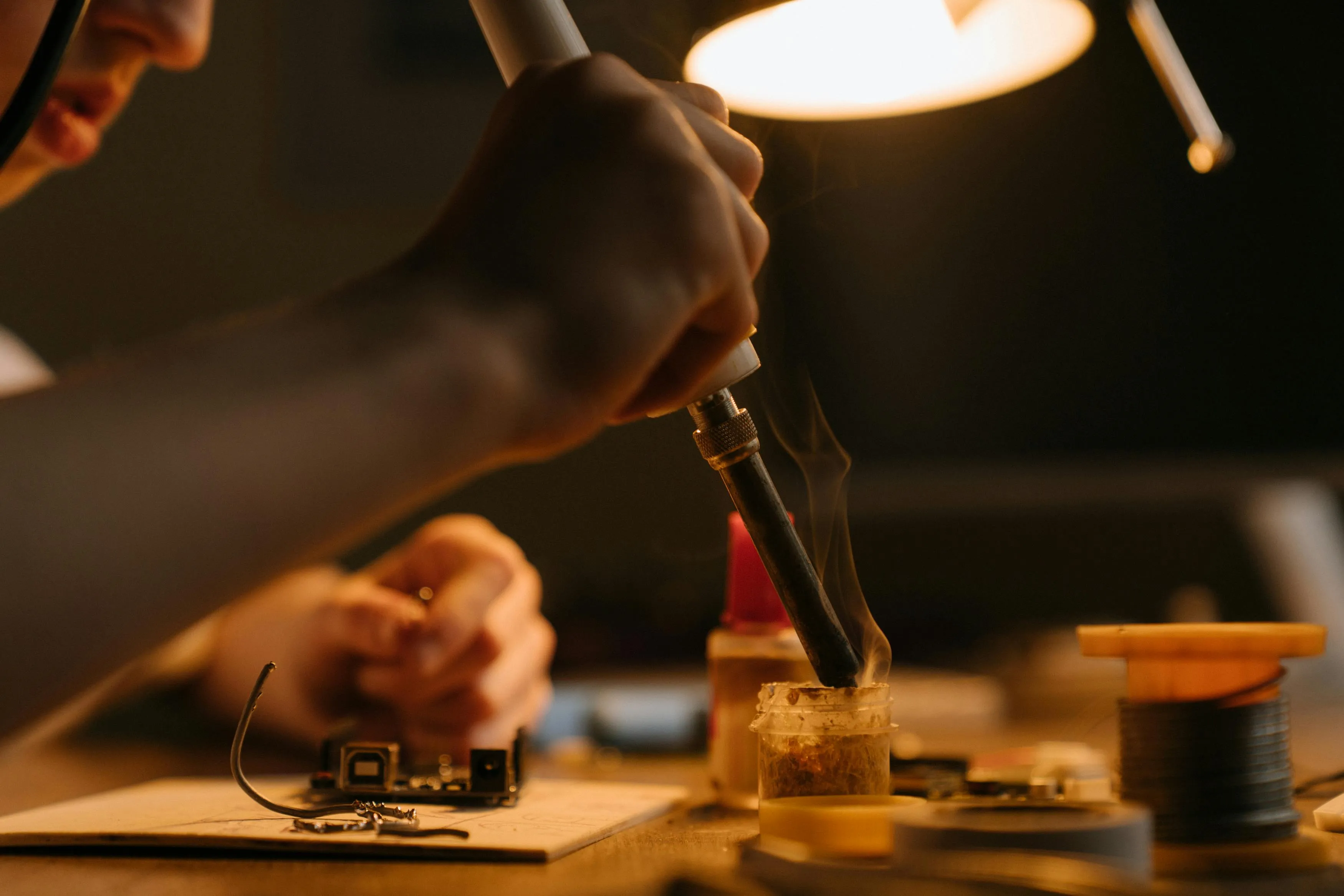 Person engaged in a hobby soldering electronics under warm light, reflecting which hobby sounds most appealing concept.