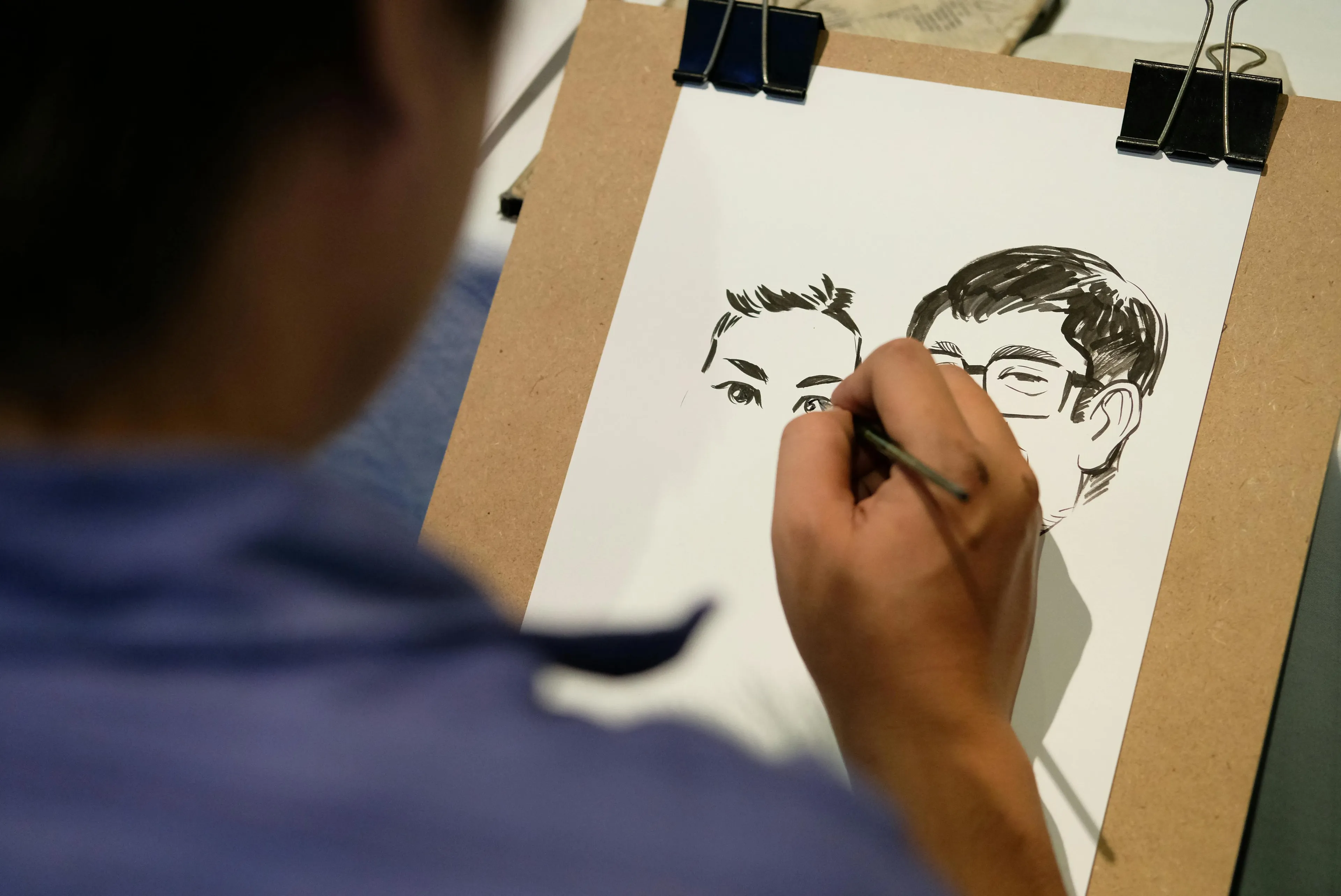 Artist sketching caricatures of two people on a clipboard, showcasing a secret talent related to sitcom characters.