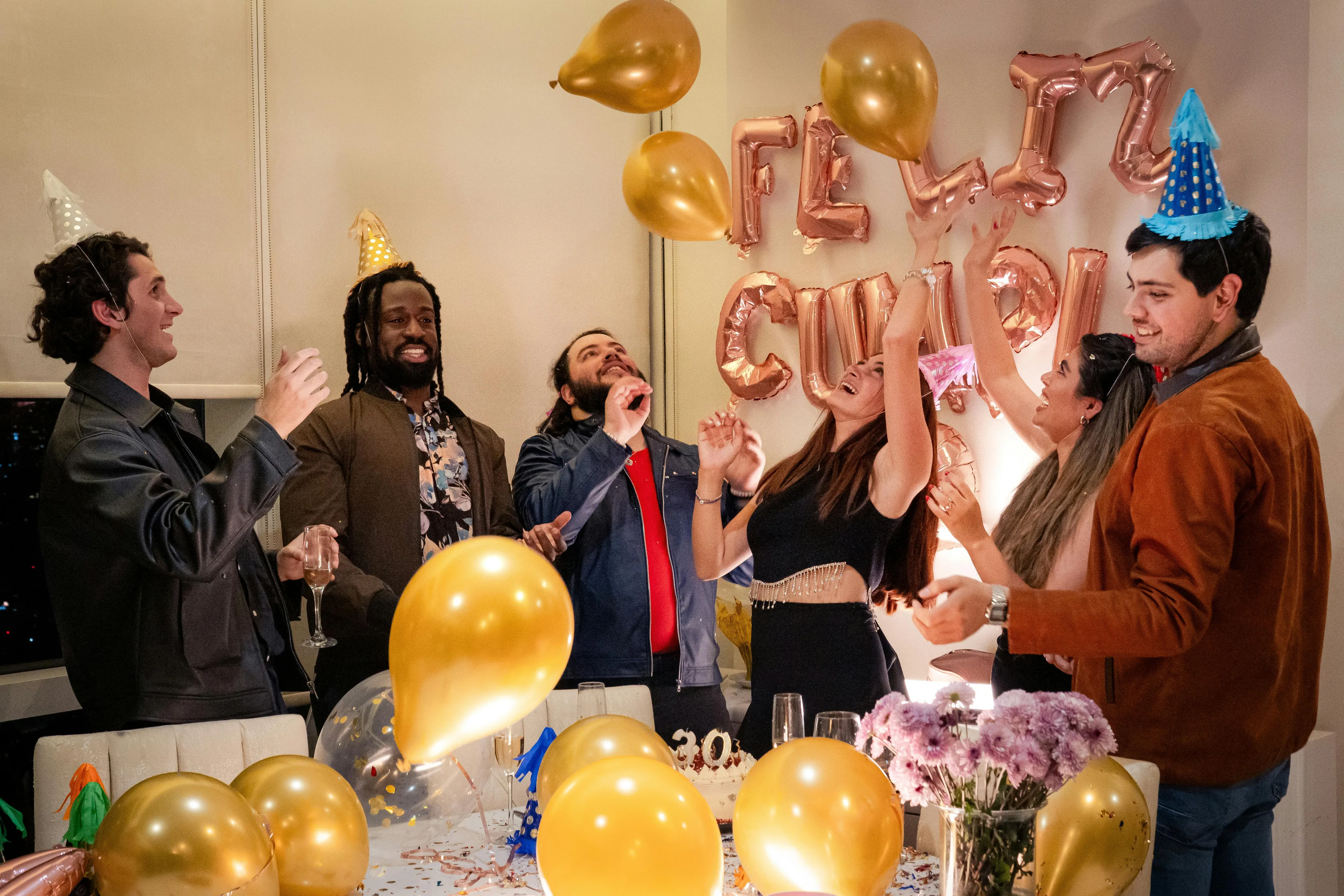 Group of friends celebrating a surprise party with balloons and laughter, capturing first reaction moments from a sitcom quiz.