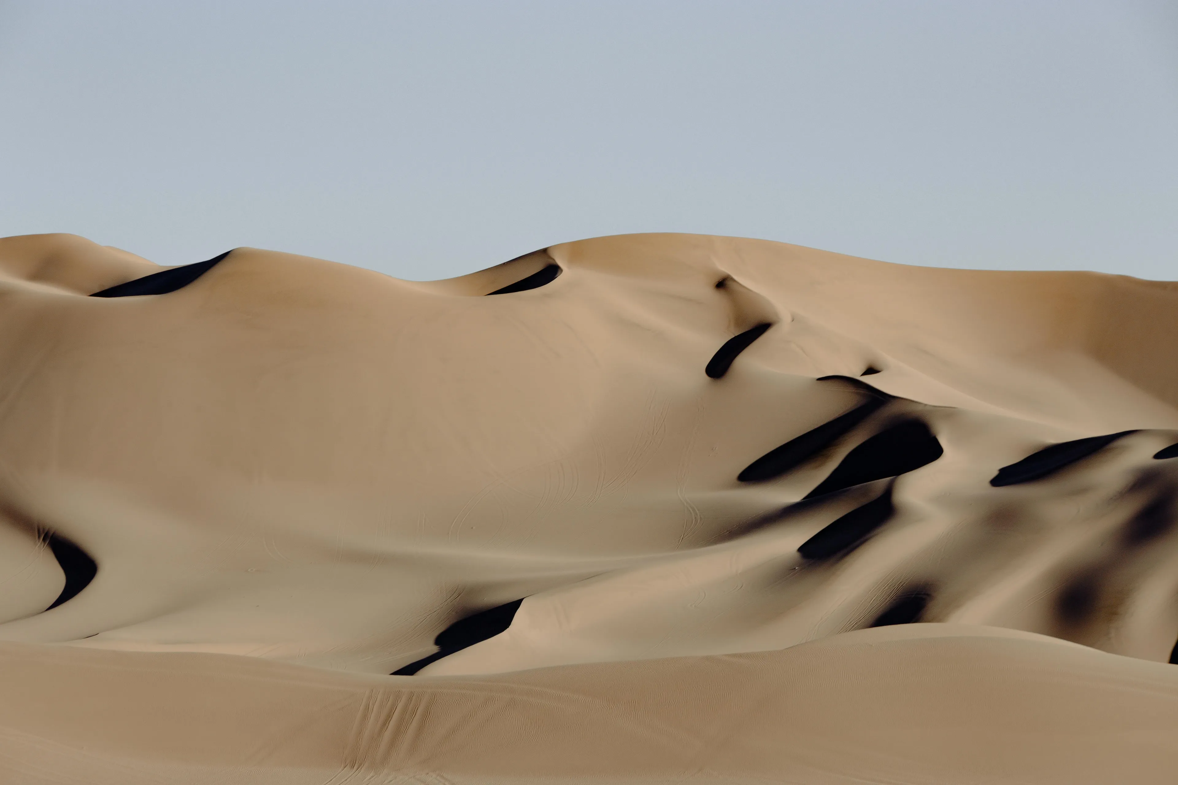 Expansive desert sand dunes under clear sky, illustrating geography true-or-false questions on deserts in Europe.