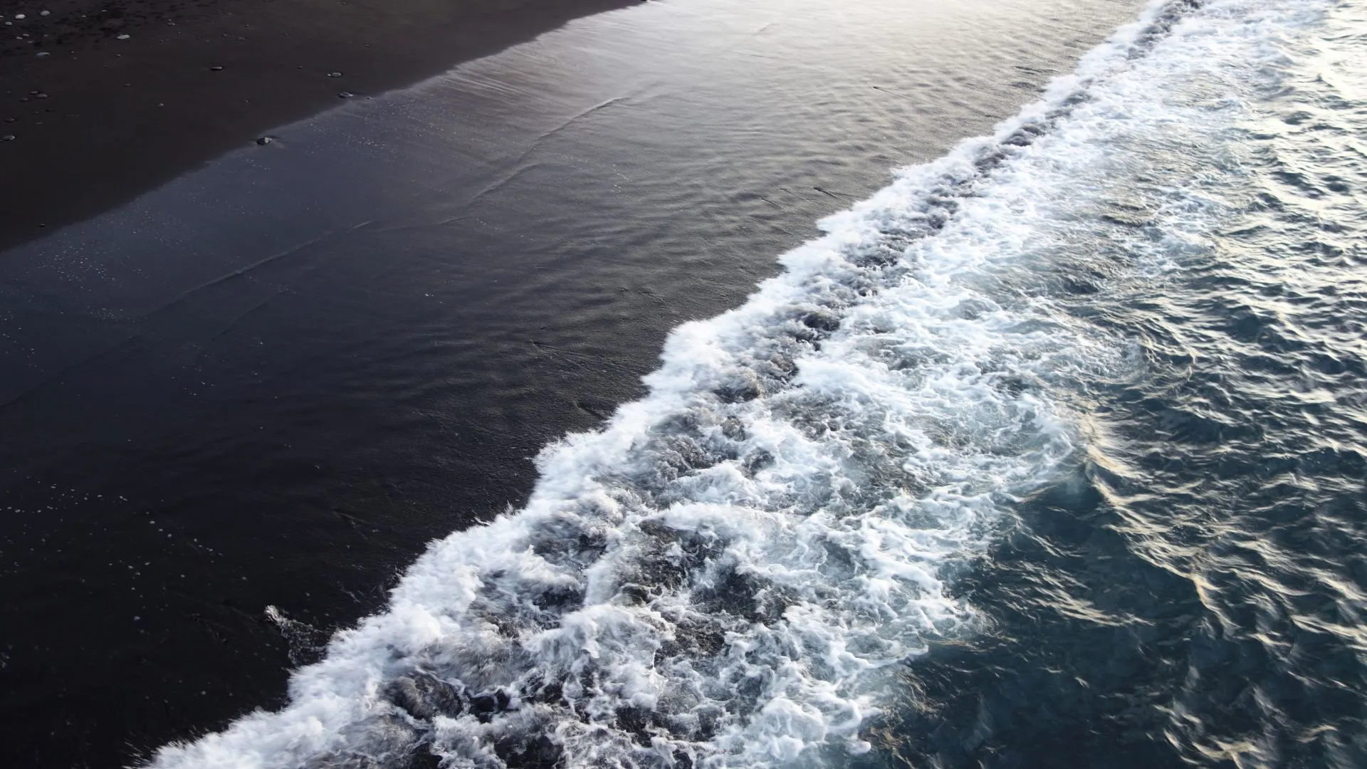 Waves crashing on dark sand beach illustrating the Black Sea coastline with no ocean outlet on modern maps.
