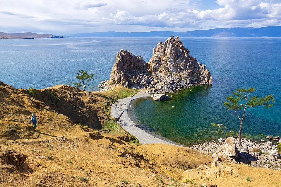 Rock formations near the clear blue waters of Lake Baikal in Russia, known for vast freshwater volume.