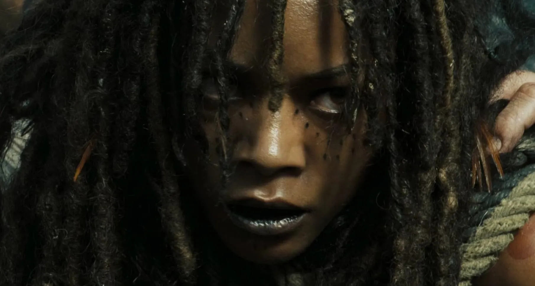 Close-up of a supporting character with face markings and dreadlocks in a dark setting guessing franchise quiz.
