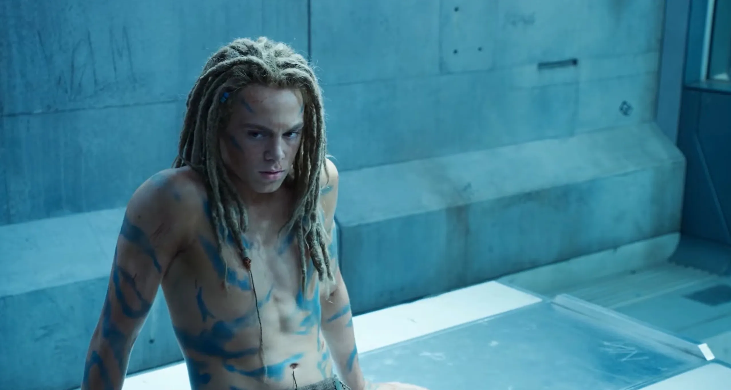 Supporting character nicknamed Spider with dreadlocks and blue body paint in a scene from a sci-fi film franchise.
