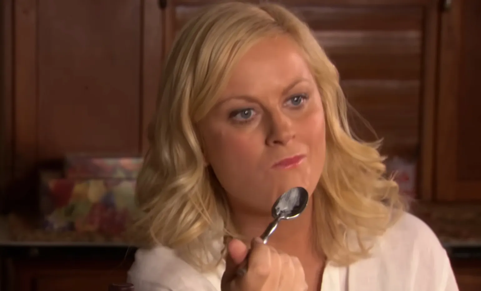 Blonde woman from Parks and Recreation eating with a spoon, highlighting side character in the show.