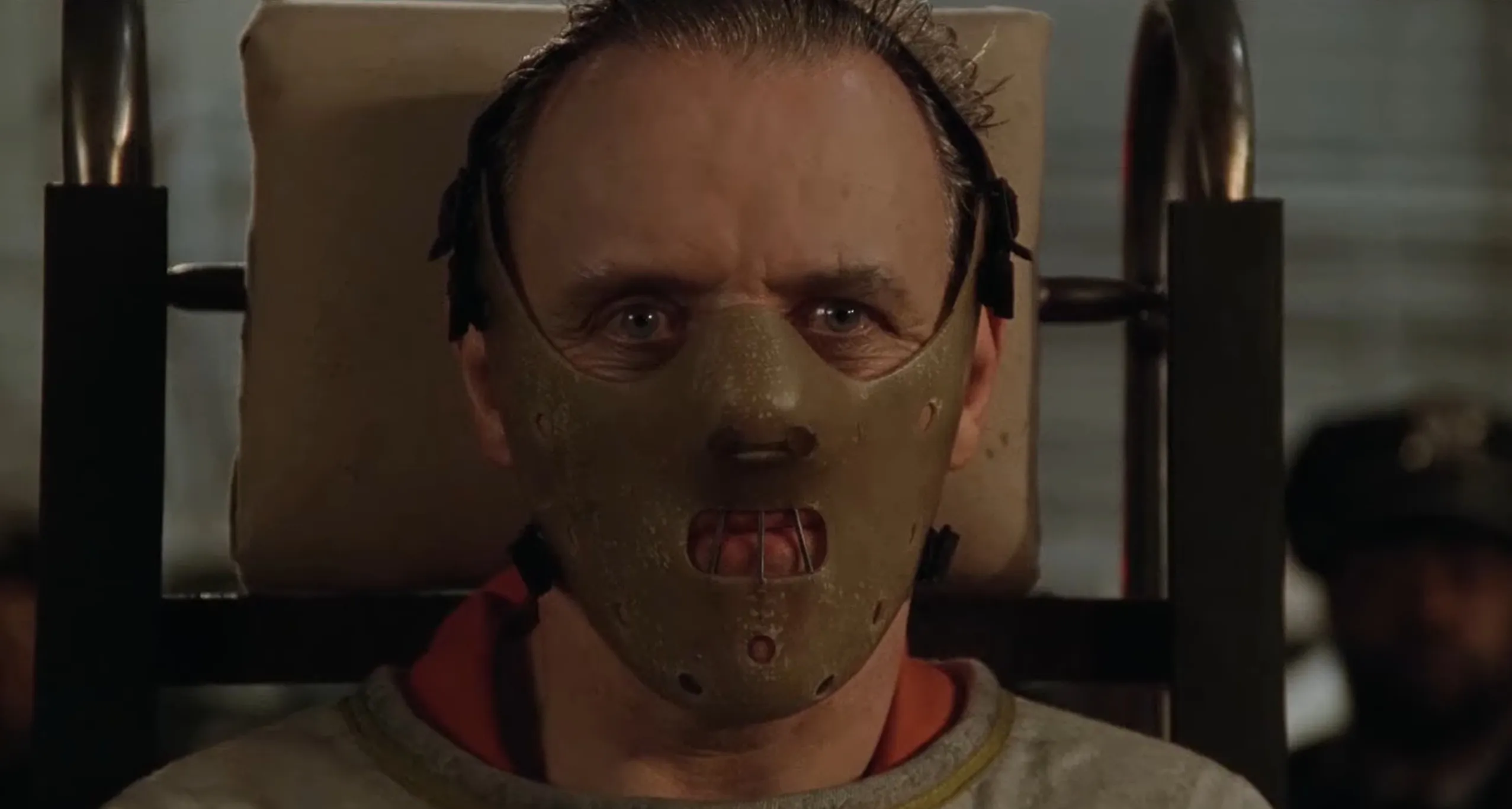 Hannibal Lecter wearing a restraining mask and chair in a suspenseful film scene, supporting character role.