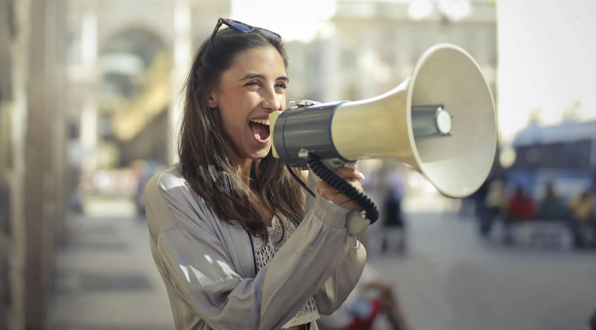 Young woman using megaphone outdoors, promoting geography quiz about countries with Portuguese as an official language