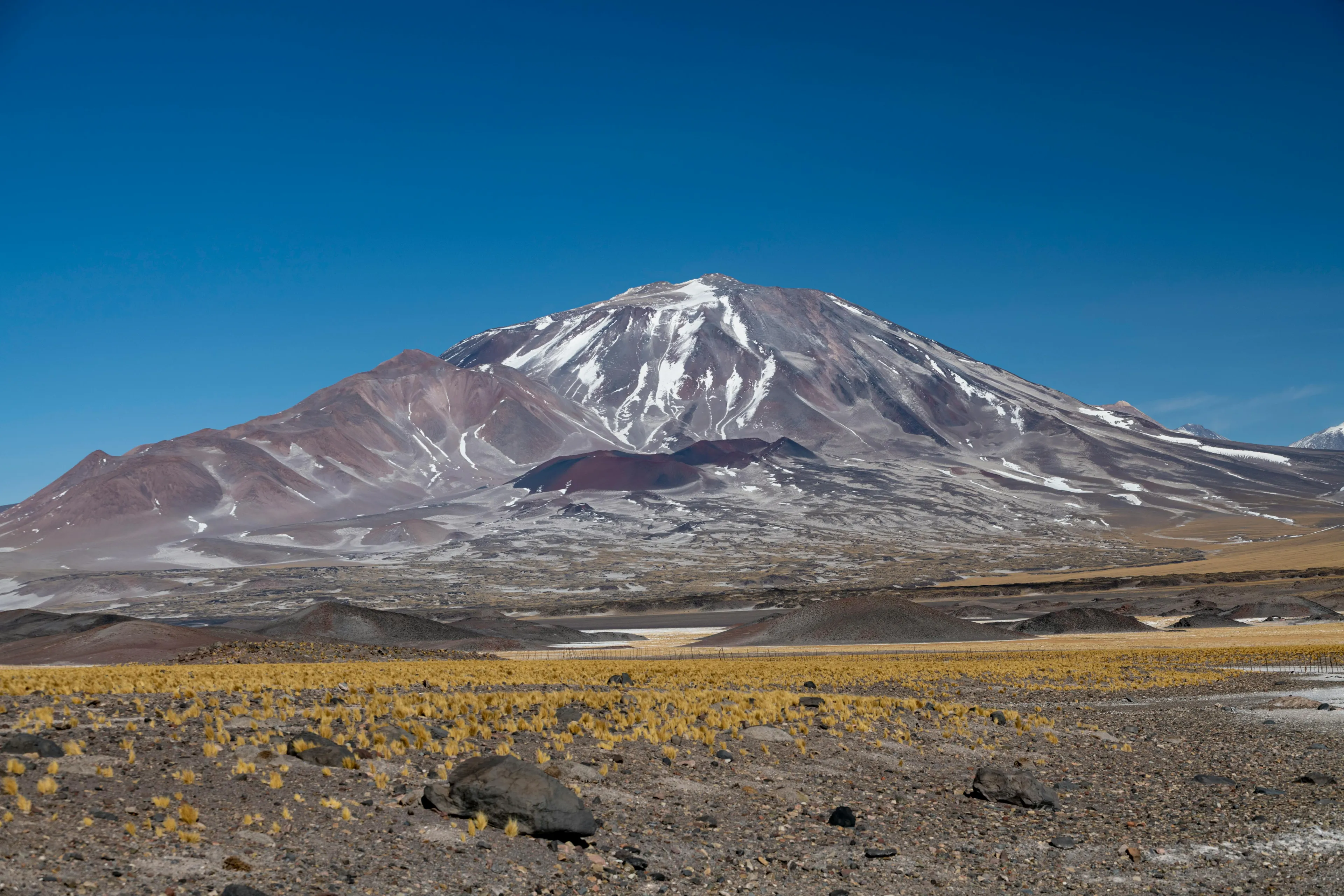 View of the Andes mountains with snow patches under a clear blue sky in South America’s western region.