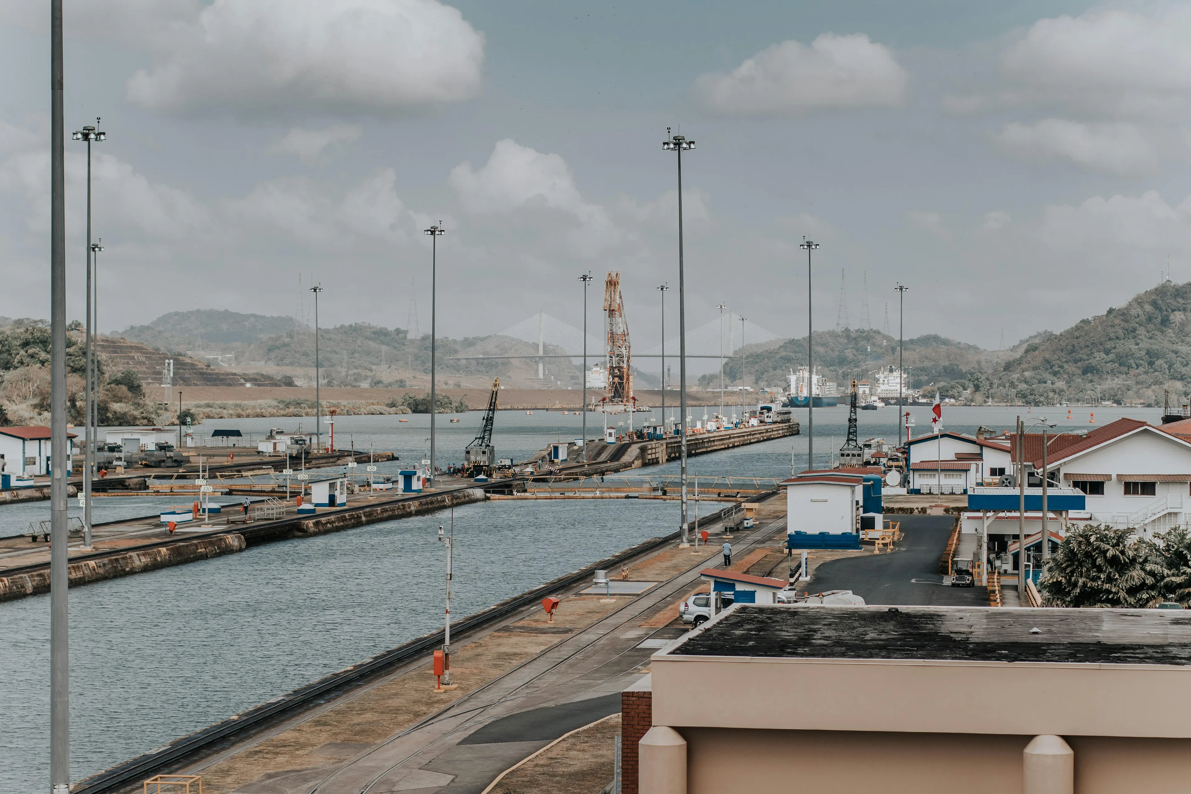 Cargo ships passing through the Panama Canal, the land bridge connecting North and South America, with hills in the background.
