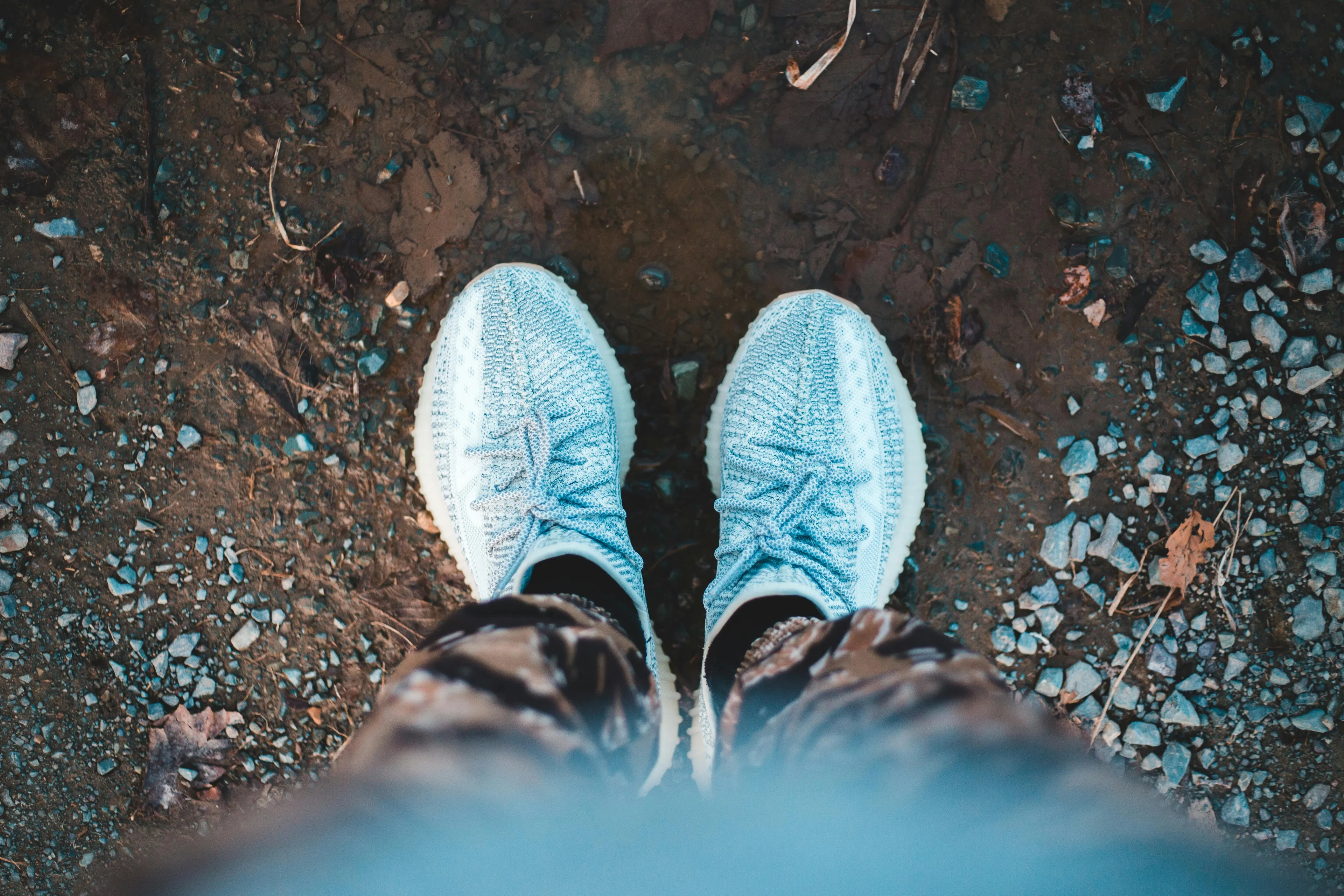 Person standing on rocky ground wearing blue sneakers and camo pants, illustrating geography true-or-false question concept.