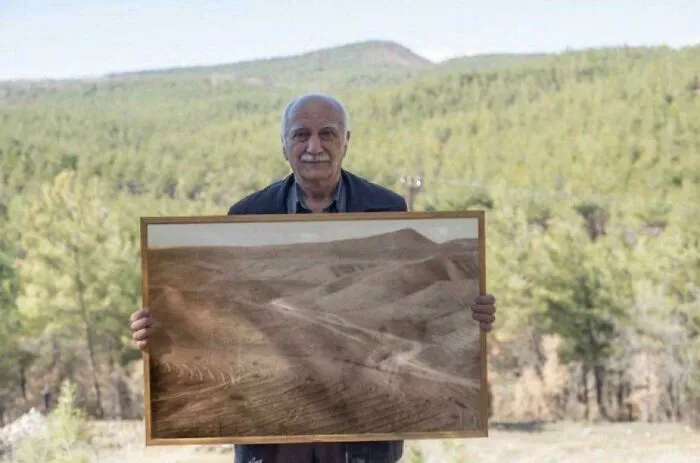 Man Posing With Picture Of Forest He Restored