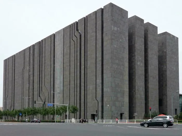 Massive dystopian urban hell building with dark, monolithic architecture towering over a sparse city street intersection.